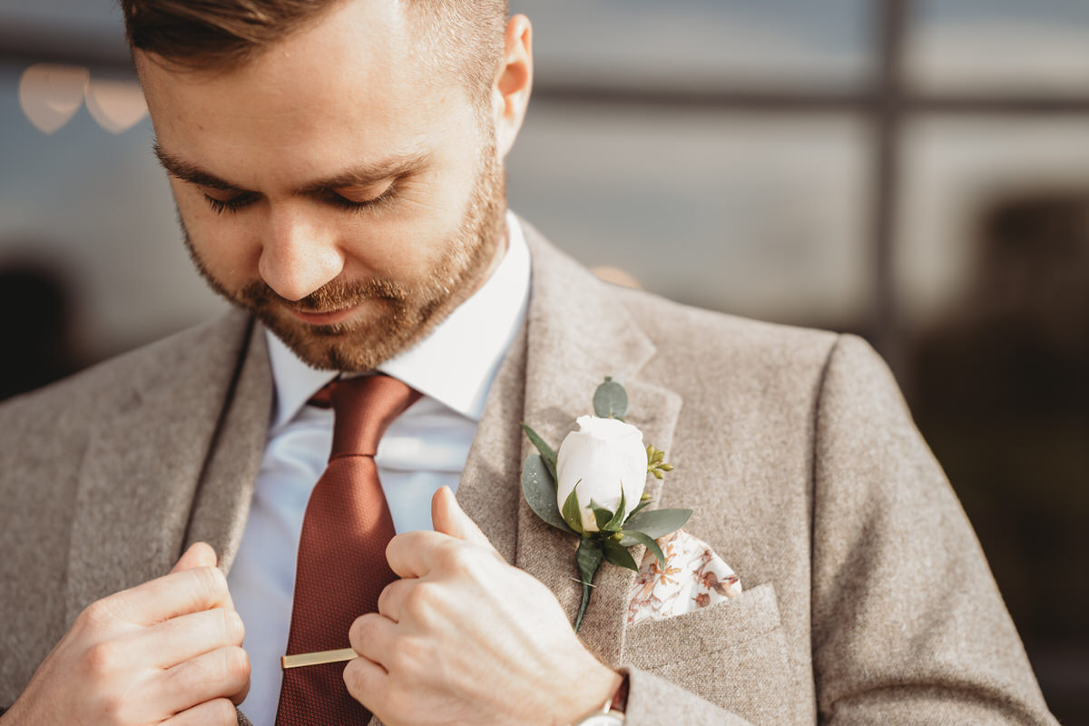 a close up of a groom adjusting the jacket to his three piece suit before his wedding at Botley Hill Barn