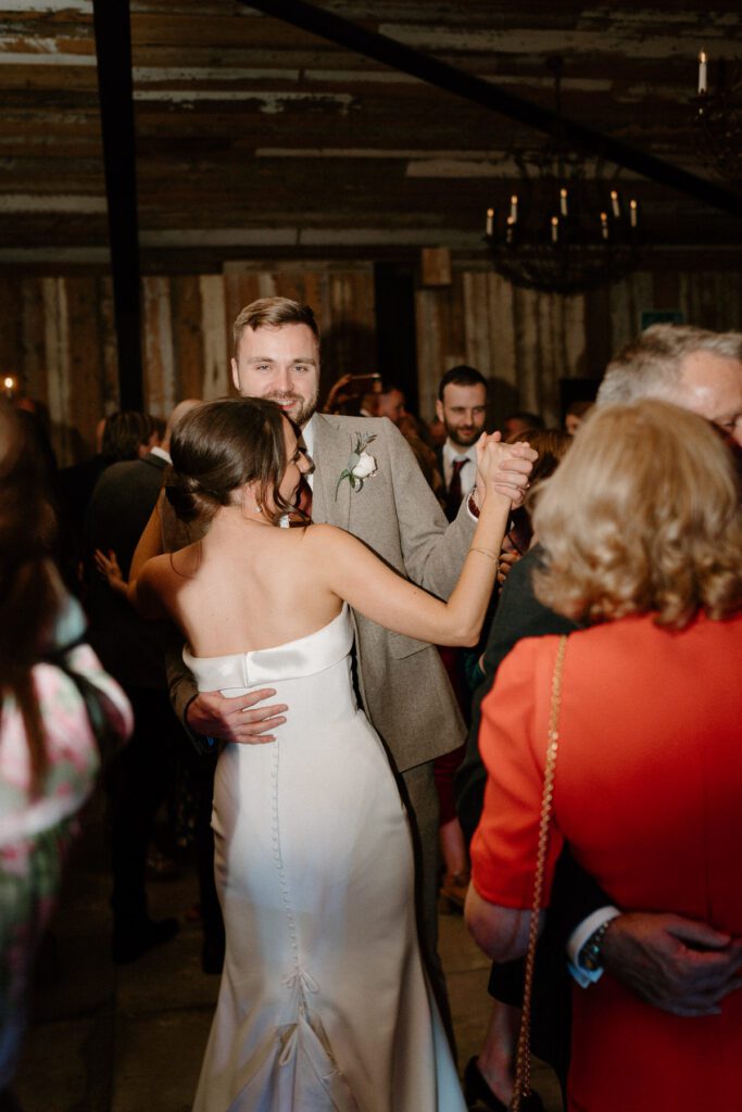 a bride and groom dancing together in the middle of a packed dance floor of guests