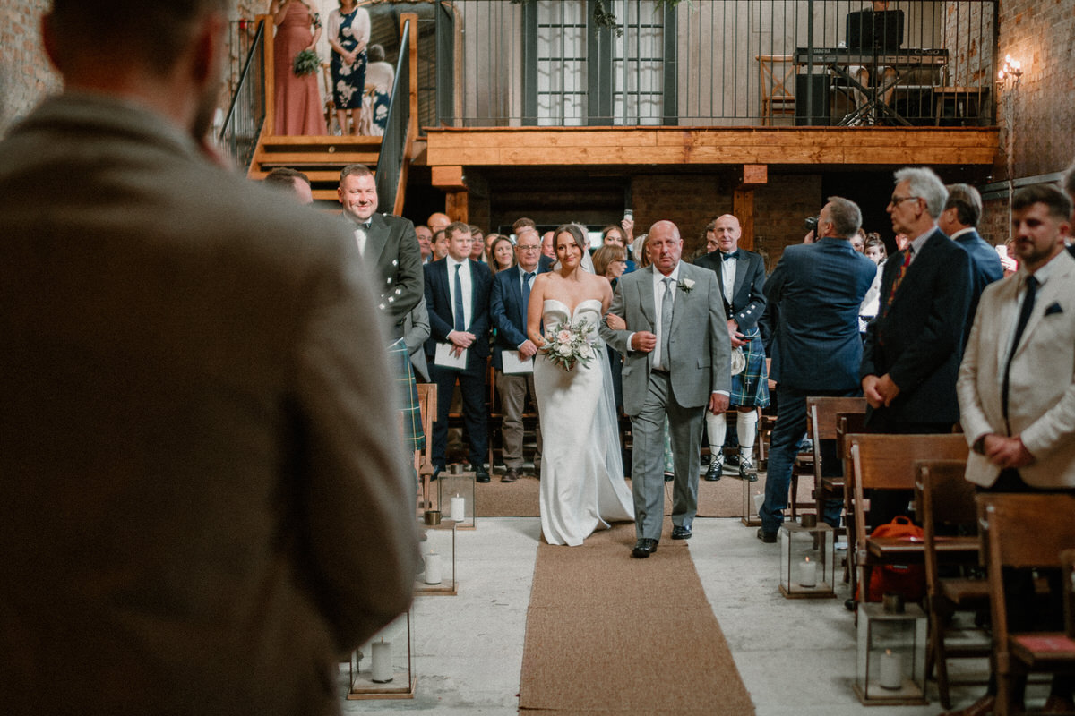 a bride walking down the aisle with her dad, smiling 