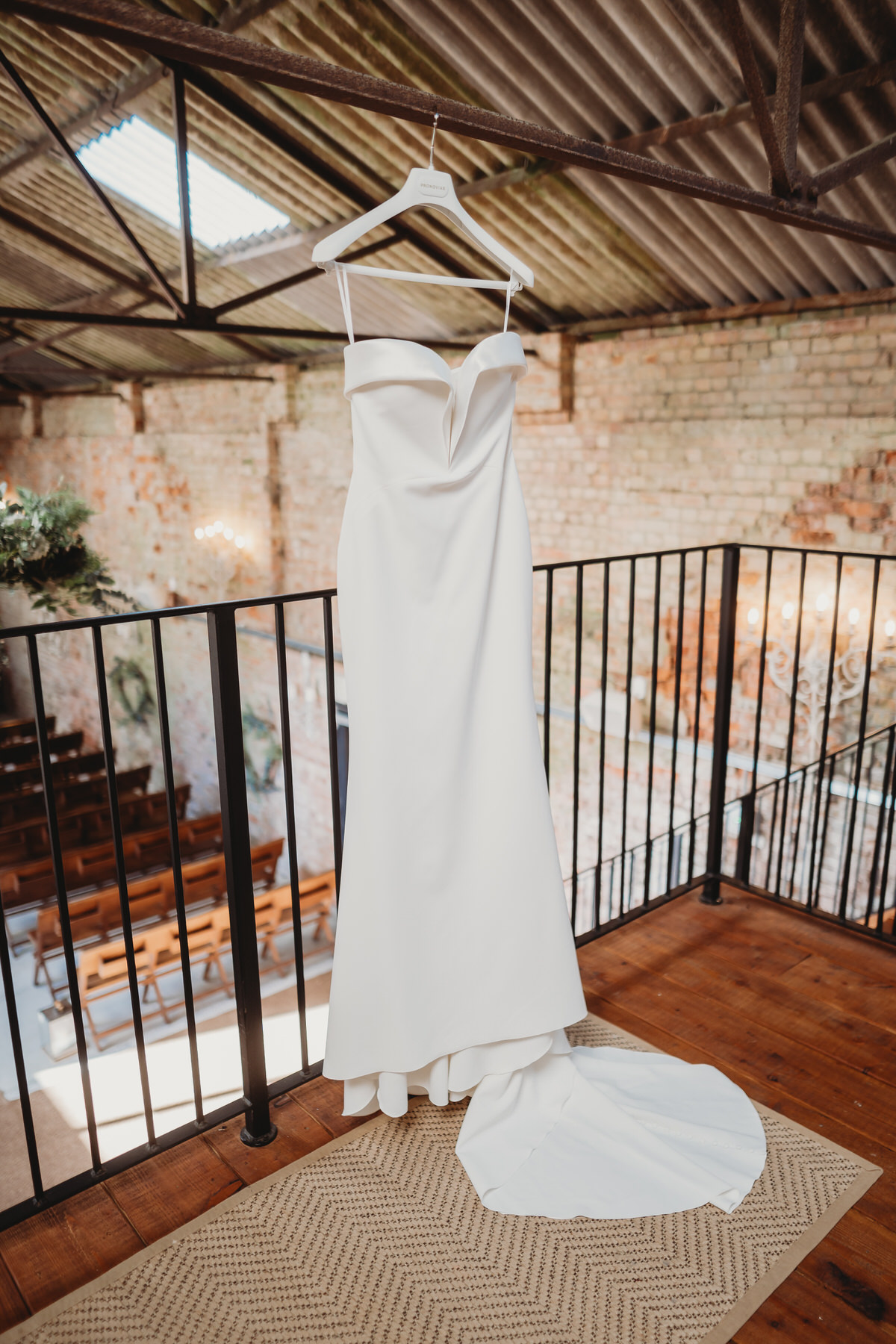 a wedding dress hanging up in a ceremony room at Botley Hill Barn photo taken by a luxury wedding photographer 