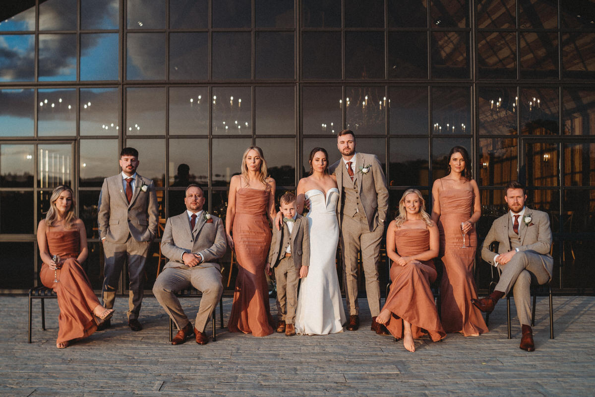 an editorial style wedding party group photo in front of barn windows