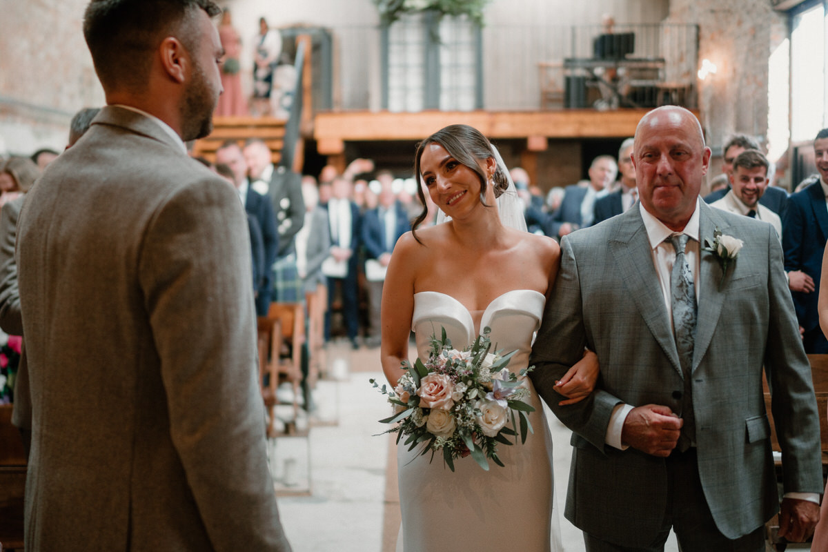 a bride looking at her husband to be with affection as shes just walked down the aisle to get married taken by Botley Hill Barn Luxury Wedding Photographer