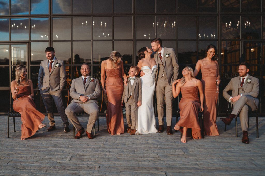 an editorial style wedding party group photo in front of barn windows