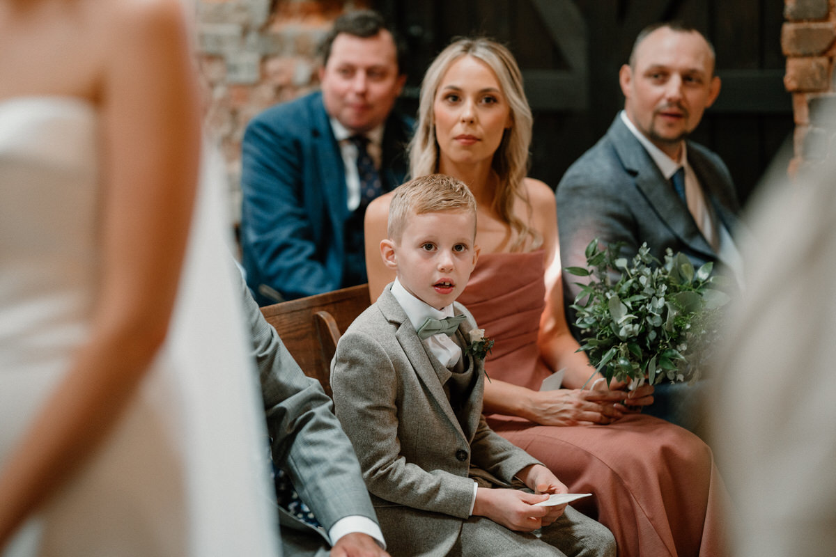 a page boy looks on as a bride and groom are getting married at a high end surrey venue