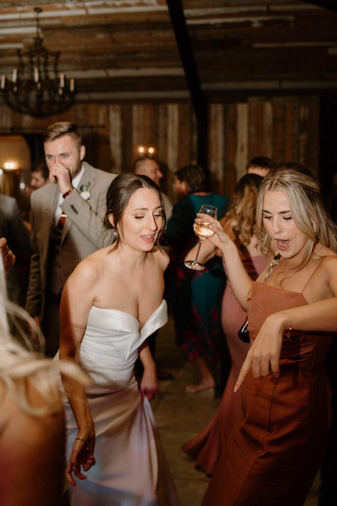 a bride singing with her bridesmaid at her wedding reception at Botley Hill Barn, a luxury wedding venue in surrey