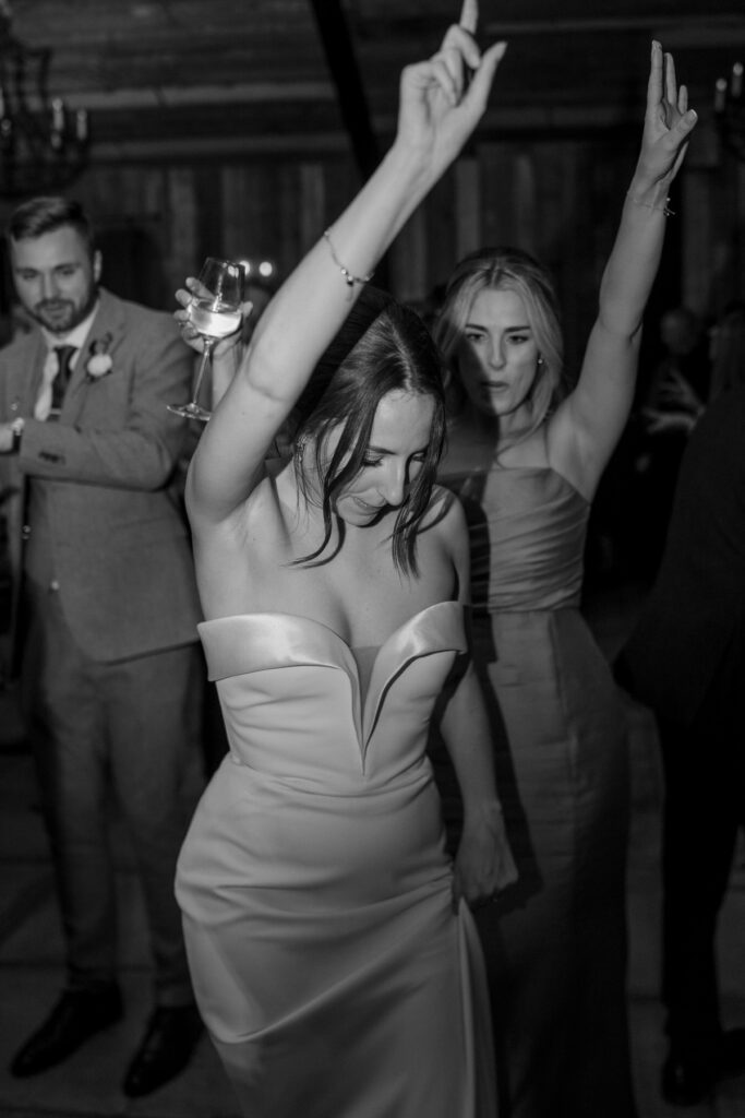 a bride lifting her hand up in the air as she sings and dances with her wedding guests