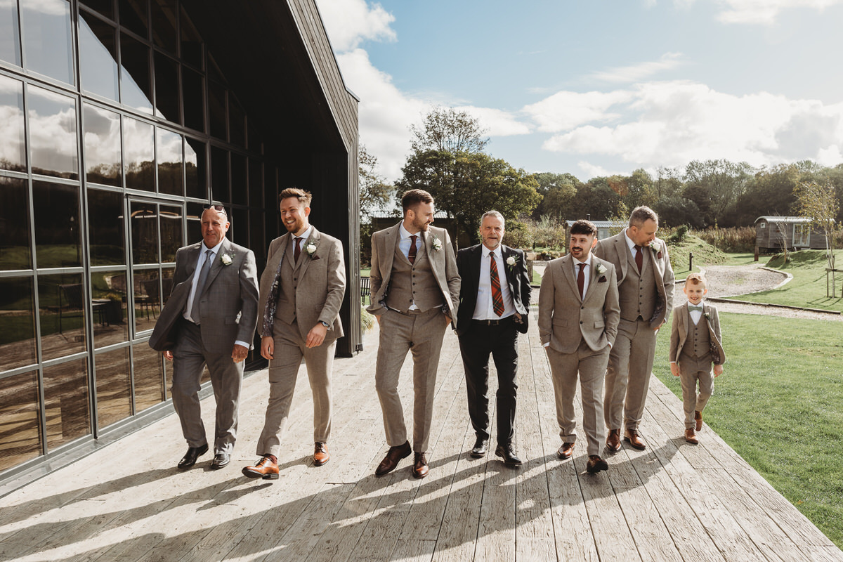 a group of groomsmen lined up walking towards the camera ready for the grooms wedding