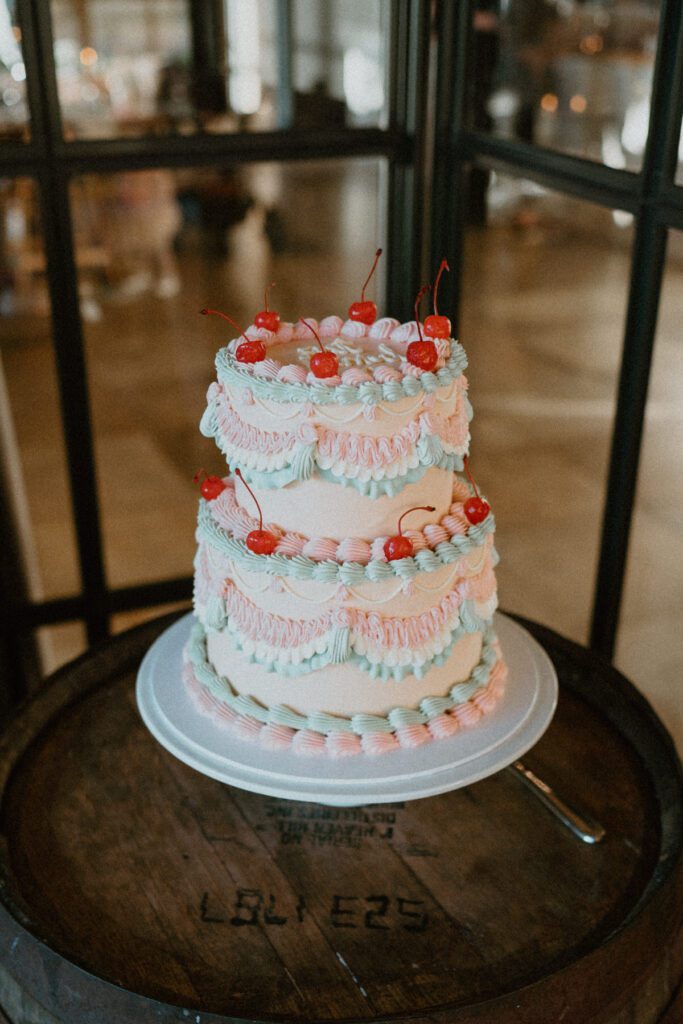 a retro white, pink and blue wedding cake, topped with cherries