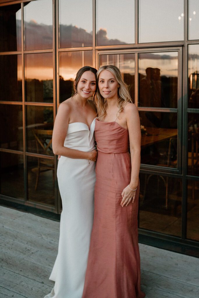 a bride and her sisters portrait photo in front of a barn window at sunset