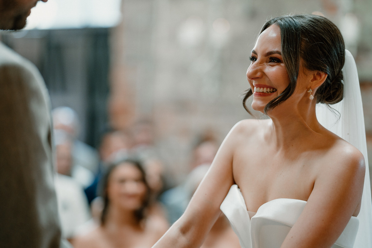 a bride giggles as she holds hand with her husband to be during their wedding service