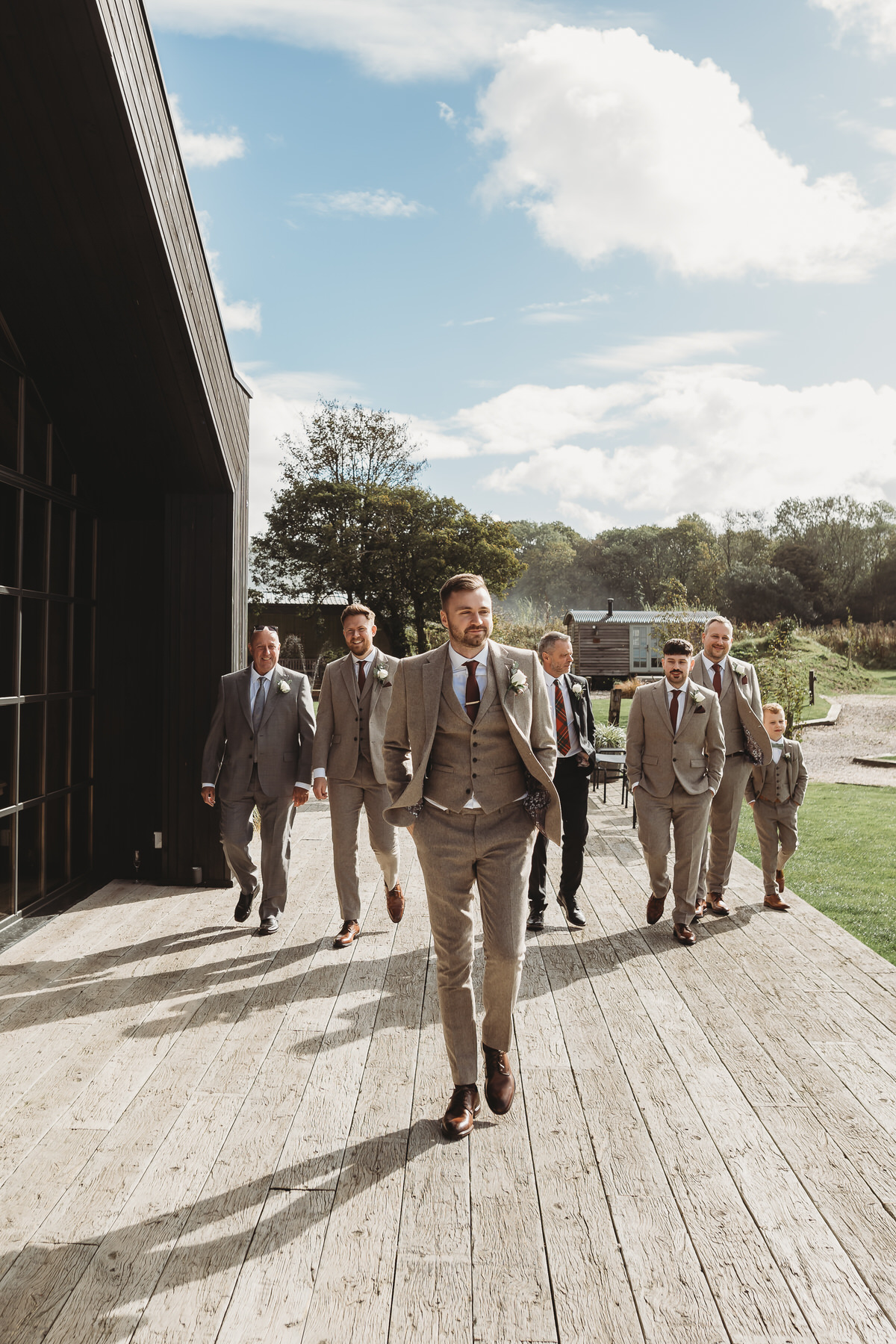 a group of groomsmen lined up walking towards the camera ready for the grooms wedding