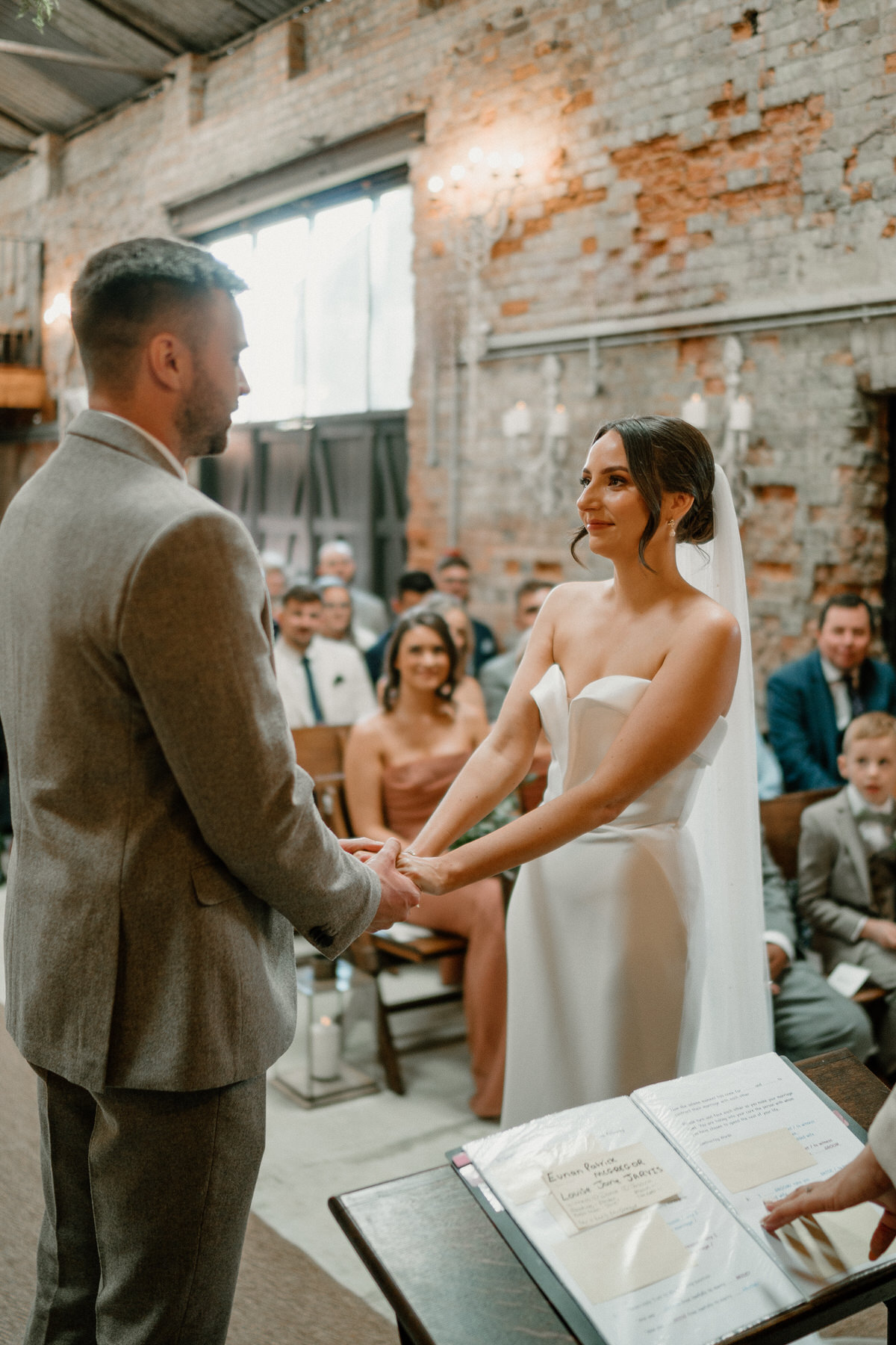 a bride and groom hold hands in front of their wedding guests as they are getting married at Botley hill Barn