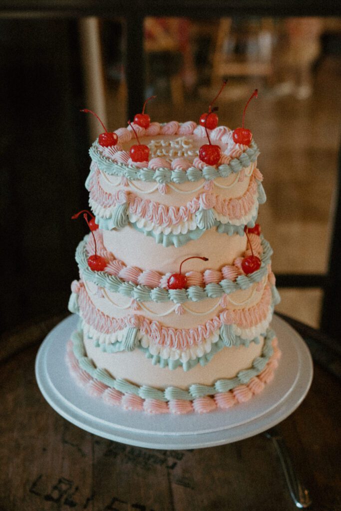 a retro white, pink and blue wedding cake, topped with cherries