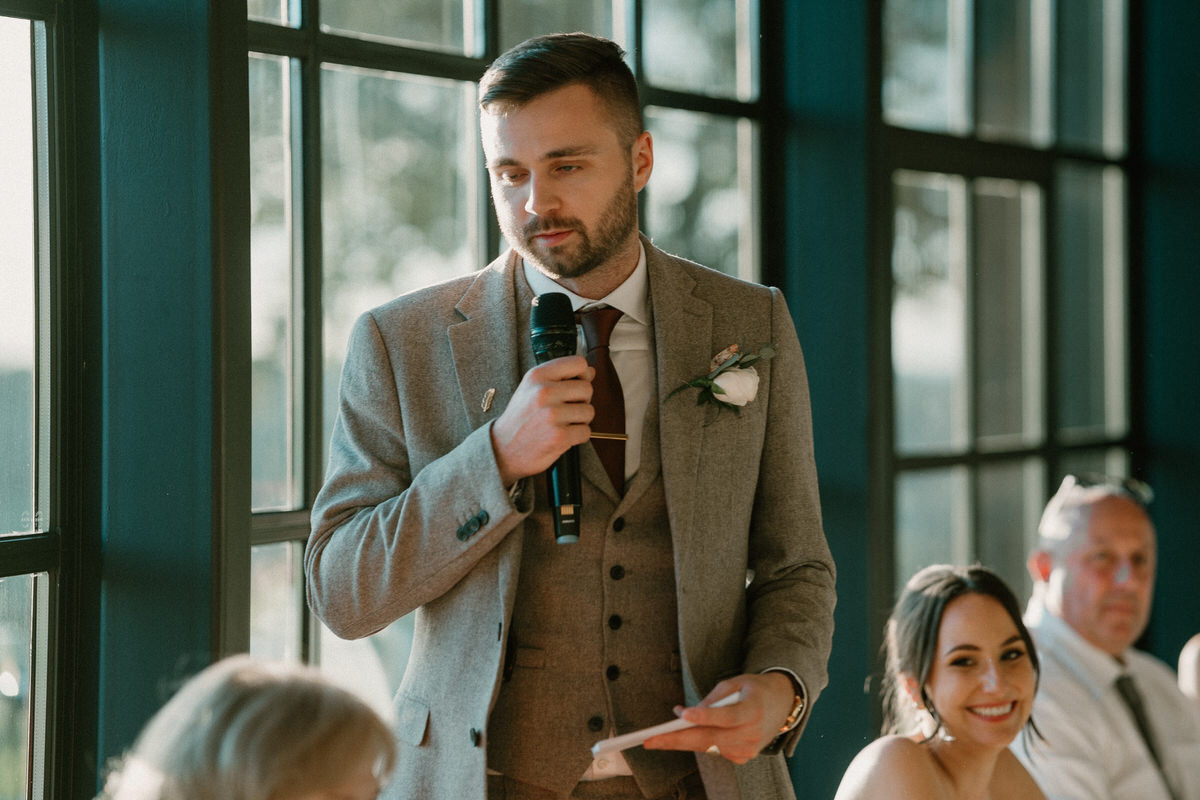 a groom looks serious as hes stood giving his speech following his wedding ceremony