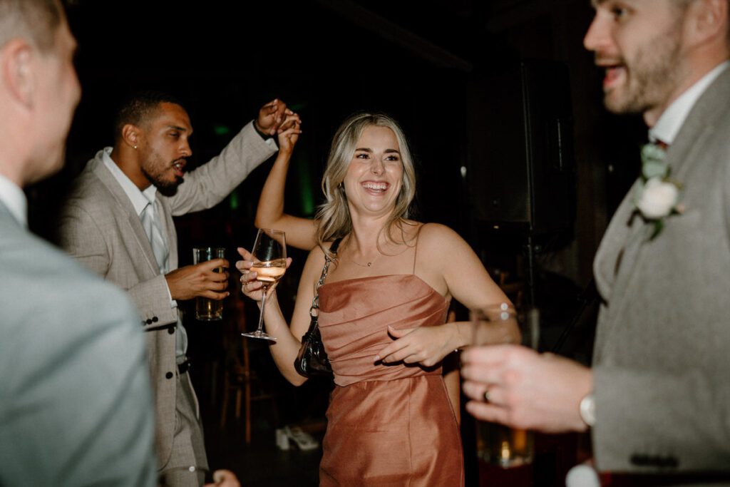 a bridesmaid dancing with a drink in her hand at a wedding reception in surrey