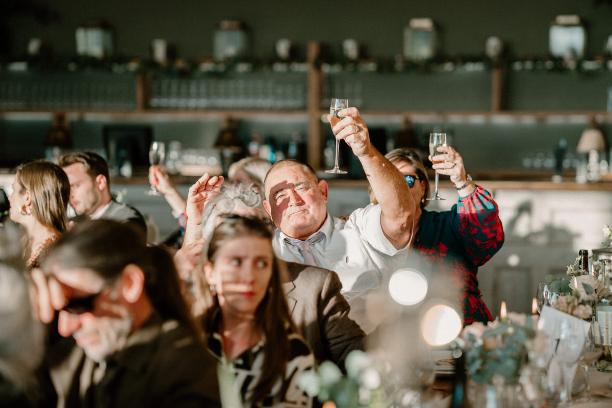 a guest raises his glass in air air to toast a wedding speech