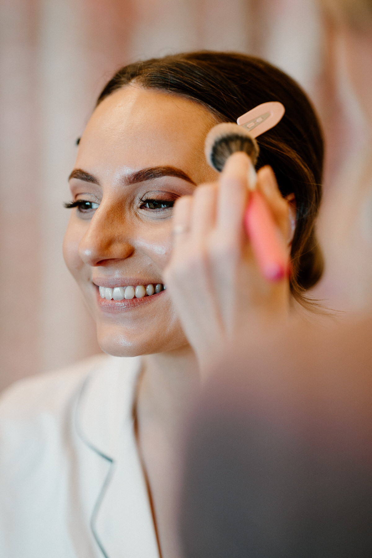 a smiling bride having her make up finished during bridal prep taken by Botley Hill Barn Luxury Wedding Photographer