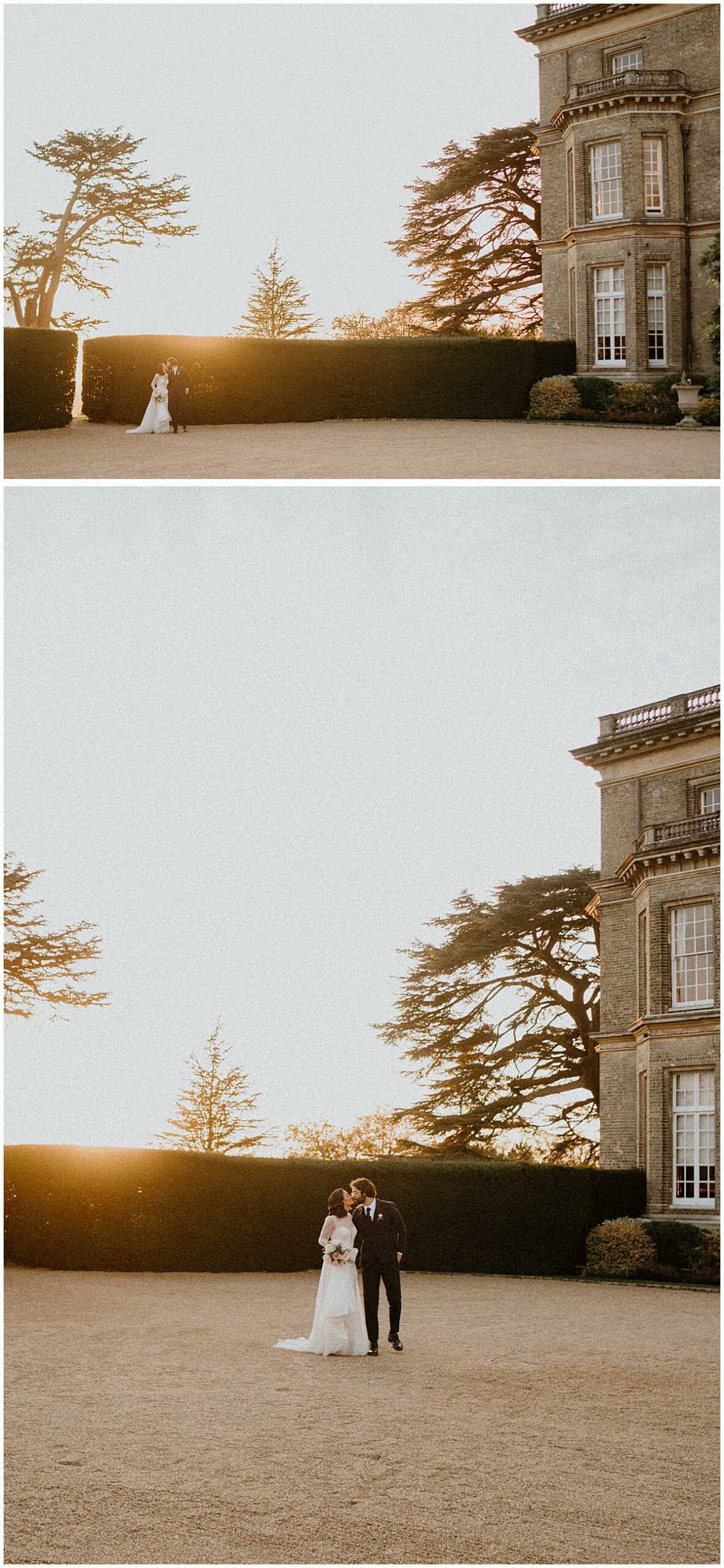 a bride and groom walking in front of hedsor house as the sun is setting