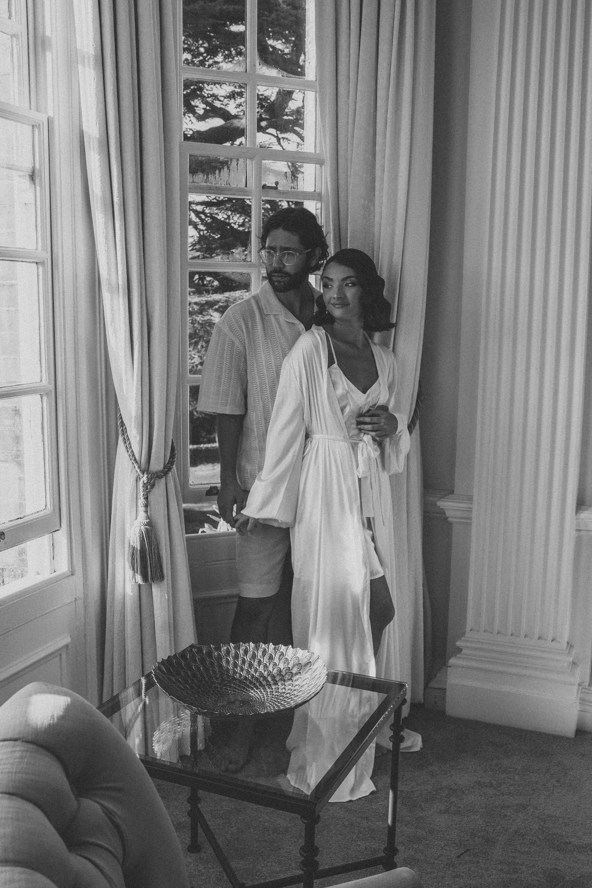 a black and white image of a bride and groom cuddling before their wedding day